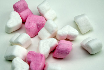 White and pink heart-shaped marshmallows lie on a white table. Pink mood.