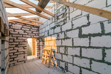 House interior under construction and renovation. Energy saving walls of hollow foam insulation blocks and bricks, ceiling beams and roof frame.