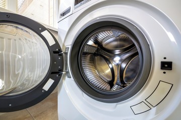 Close-up detail of modern washing machine interior with open door interior. Silver shiny stainless drum, design and technology.