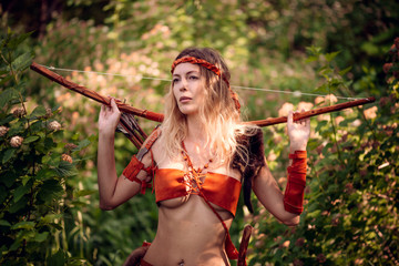 Beautiful girl archer with long blond hair with a bow and arrows dressed in leather