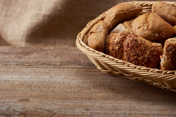delicious fresh buns in wicker box on wooden table with copy space