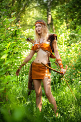 Beautiful girl archer with long blond hair with a bow and arrows dressed in leather