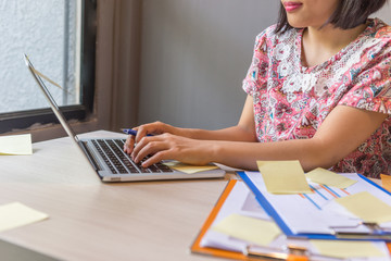 Close up photo of woman holding pen typing laptop keyboard 