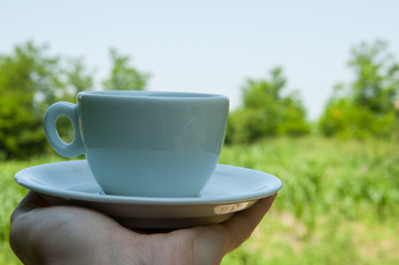White coffee cup in hand in nature.Coffee time