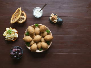 Traditional Arabic kibbeh with lamb and pine nuts. Top view. Natural wooden background