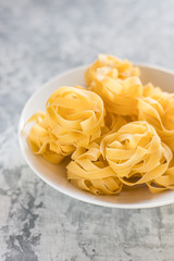 Tagliatelle raw Italian pasta on a light background.