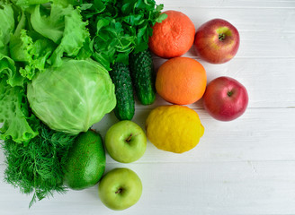 Green vegetables  and colored fruits on a white background.