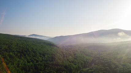 Aerial view of Caucasus mountain with haze and forest. Morning fog over the forest.