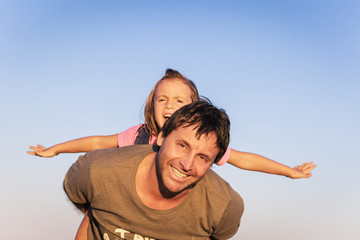 Father and daughter playing on the beach at the sunset time