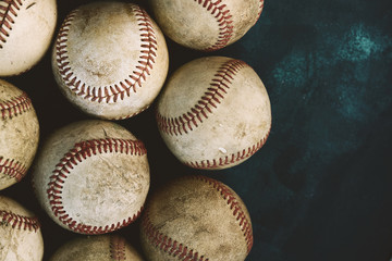 Old baseballs on dark background close up show grit of the game with copy space for text.
