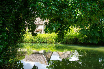 Maison en bord de ruisseau avec reflets dans l'eau
