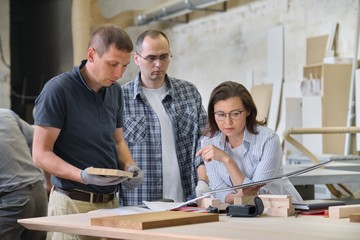 Team of carpenters workshop workers discussing a furniture project with client, designer, engineer.