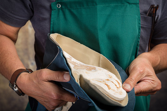 close up of orthopedic shoemaker covering a wooden last with leather