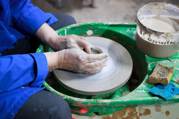 A novice student in the first lesson in pottery tries to make a product from clay on a potter's wheel. reportage. Incorrect hand setting