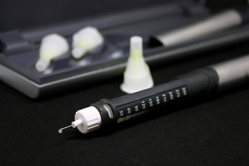 Insulin pen with needles. Selective focus close up on black background. Medical devices are used for self-use in the treatment of diabetes. health care concept