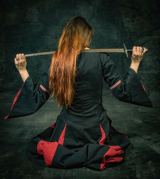 Kneeling Woman Holding A Sword Over Her Shoulders