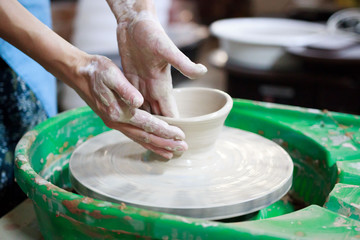 A novice student in the first lesson in pottery tries to make a product from clay on a potter's wheel. reportage. Incorrect hand setting