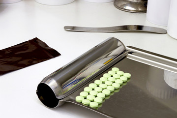 Drug pills on counting tray with spatula and dark plastic zipper bag on counter pharmacy shop