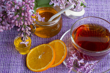 a jar of fragrant flower honey. Honey saved and lilac flowers. Cup of black tea.