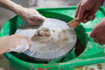 A novice student in the first lesson in pottery tries to make a product from clay on a potter's...
