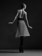 Ballerina in black tights and white dress   standing back