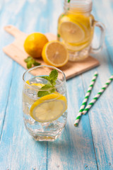 Fresh lemonade with lemon in glass on wooden background