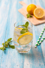 Fresh lemonade with lemon in glass on wooden background
