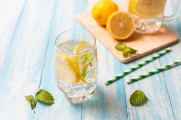 Fresh lemonade with lemon in glass on wooden background