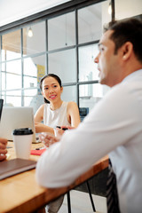 Obraz premium Asian mature man sitting at the table and talking to his colleagues during a business meeting at office