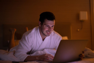 Man chatting on laptop in bed instead of sleeping, late night