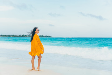 Young beautiful woman on tropical seashore in sunset.