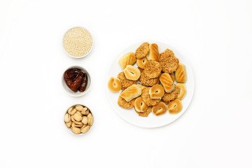 Traditional oriental cookies with sesame, dates and pistachio on a white table, top view