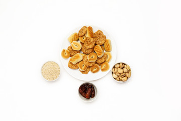 Traditional oriental cookies with sesame, dates and pistachio on a white table, top view