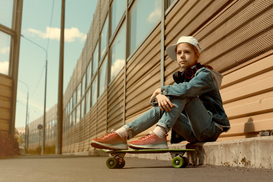 Teen on skateboard in jeans clothes, on the background of industrial