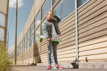 Teen on skateboard in jeans clothes, on the background of industrial