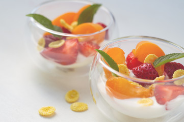 Vitamin dessert of fresh strawberries, apricots and cornflakes with yogurt on a white background