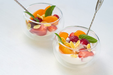 Vitamin dessert of fresh strawberries, apricots and cornflakes with cream on a white background