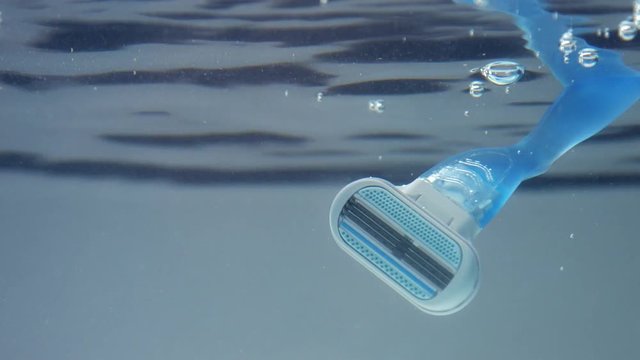 woman shaver immerced into watr. underwater view. moving razor under water