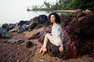 Young asian woman sitting on the coast of a tropical sea beach.