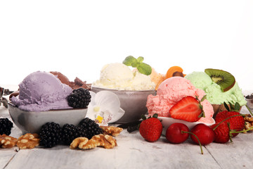 ice cream scoops of different colors and flavours with berries, nuts and fruits decoration on white background