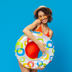 Happy black millennial woman in swimwear holding colorful inflatable ring