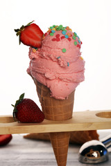 Strawberry ice cream scoop on a rustic white background with fresh strawberries