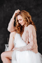 Studio shot of beautiful young woman with blonde hair wearing loose long-sleeved sweater over white...