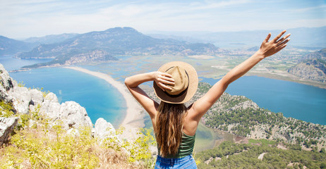 Happy woman with hands up standing on cliff over sea and islands at summer. Vintage mood, concepts...