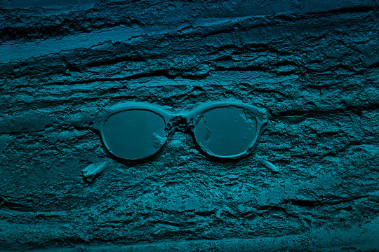 Sunglasses sunk in wet dark blue cement
