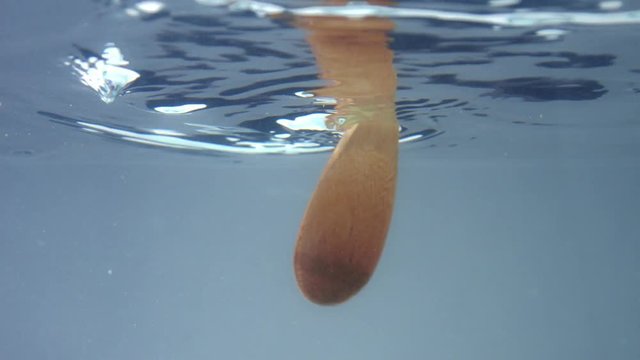 a wooden spoon immerced in water and mix it. Underwater view