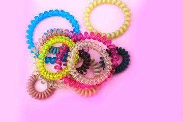 Plastic spiral colored colorful scrunchies for women hairdressing hairstyle on pink background with free copy space for text