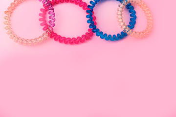 Plastic spiral colored colorful scrunchies for women hairdressing hairstyle on pink background with free copy space for text