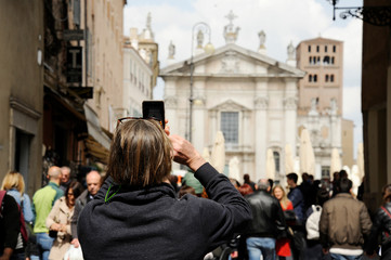 Primo piano del turista uomo sulla strada a Mantova, prendendo foto di Piazza Sordello con il telefono. Mantova, Italia