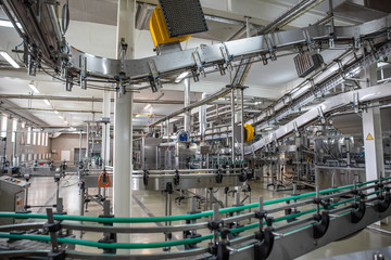 Modern beverage factory or plant interior with special industrial food production equipment. Automated conveyor belt with juice in bottles
